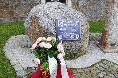 Gedenkstein mit Blumenkranz